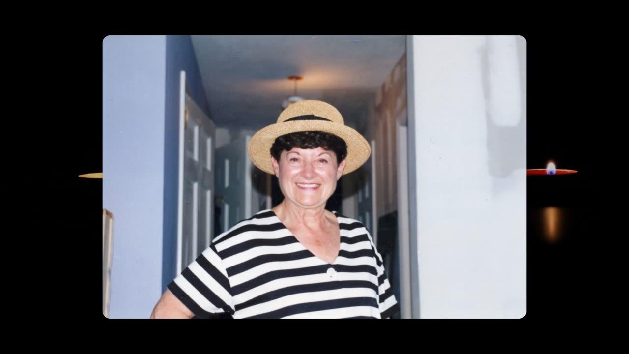 A smiling woman in a straw hat, one photograph from a memorial slideshow, framed by candlelight