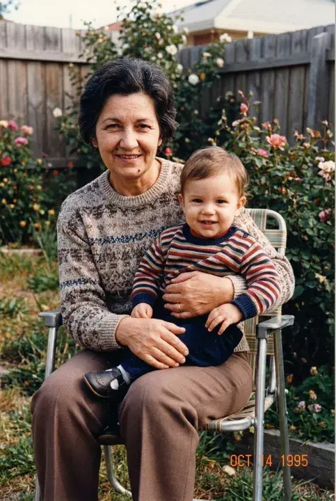 A woman in a garden chair holding a small child on her lap