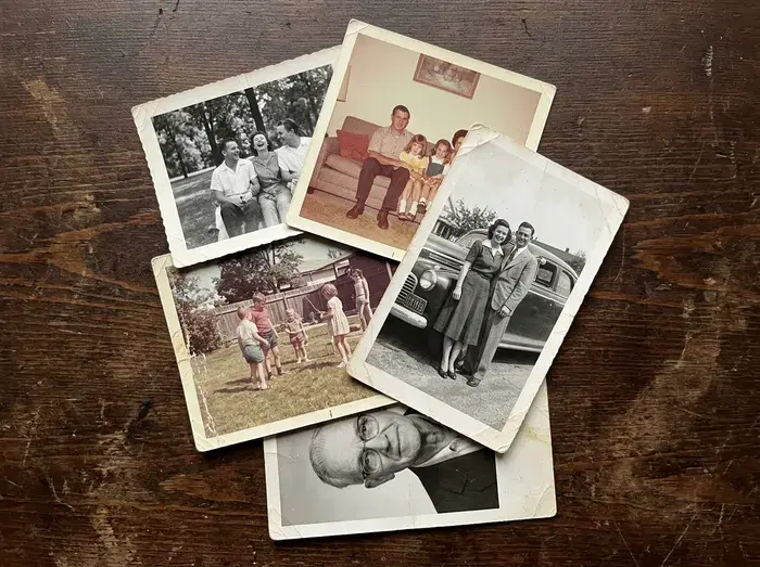Printed photographs piled on a table, overlapping one another.