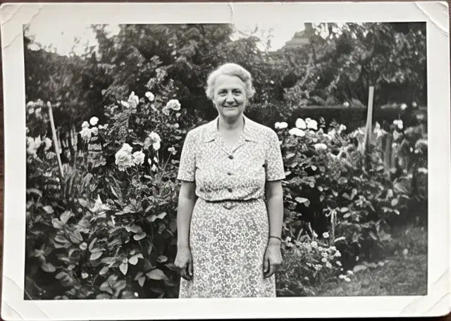 Black and white print of a woman standing in a flower garden.