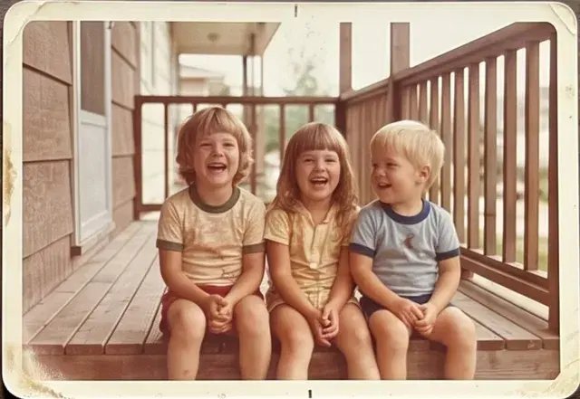 Faded colour print of three children laughing on a porch.